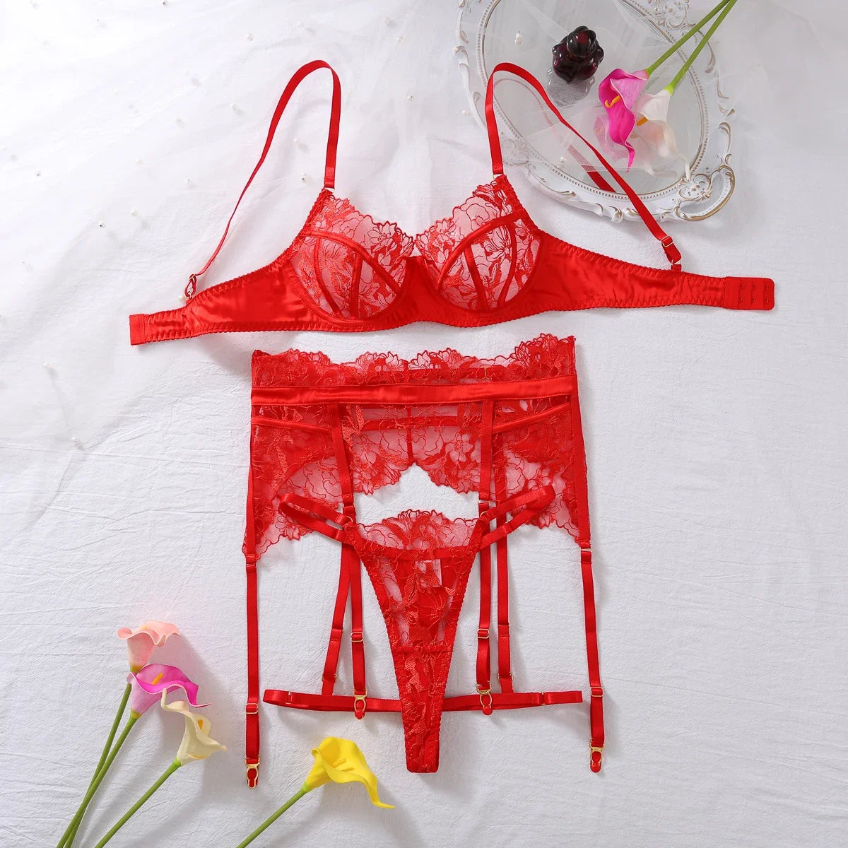 Three-piece sheer red lingerie set with underwire bra, lace garter belt and thong on a white background