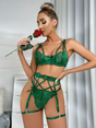 Model wearing emerald green lingerie set with bows, holding a red rose