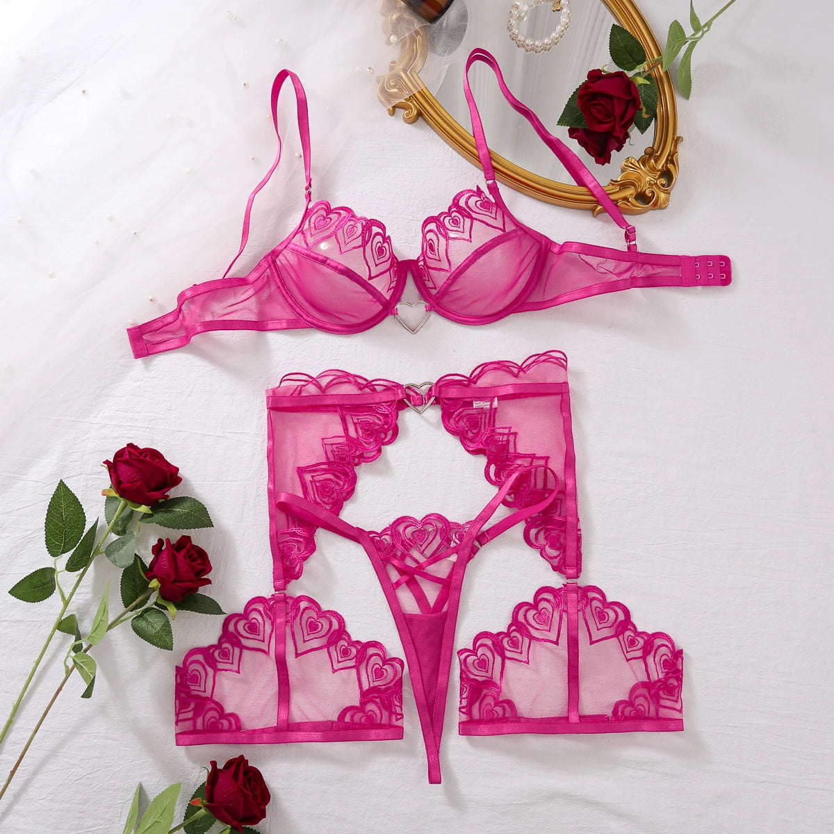 Flatlay of the pink heart lingerie set with sheer mesh, heart embroidery and accessories